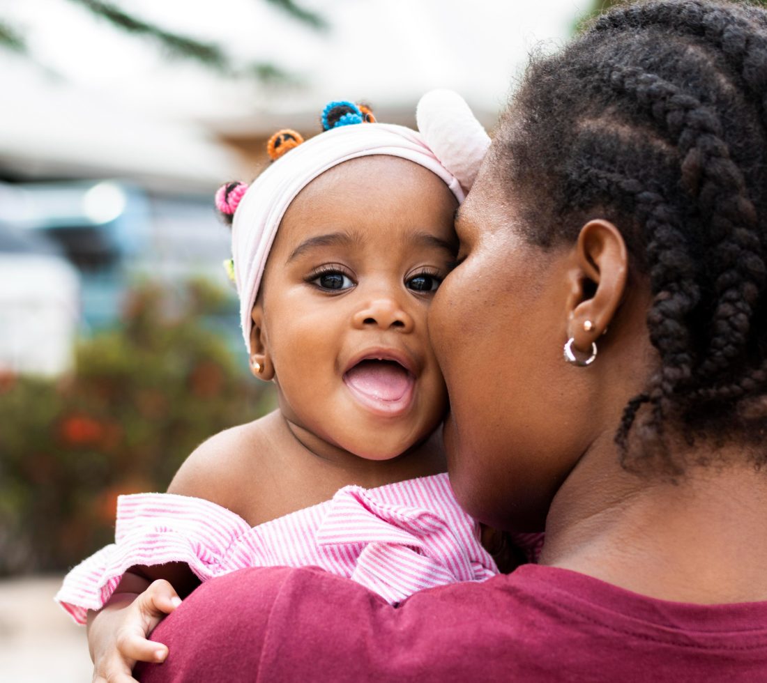 A mother holding and kissing her young daughter